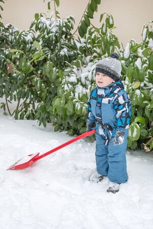 Adorable toddler boy happy about snow in winter, outdoorsの写真素材