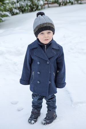 Little boy of two years in winter clothes on day with lot of snowの写真素材