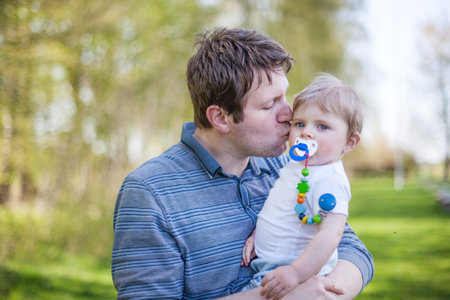 Young father and sweet baby boy in spring forest on sunny warm day