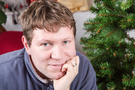 Portrait of beautiful young man smiling indoor with Christmas tree