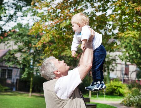 Happy grandfather with little baby boy in summer gardenの写真素材