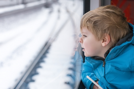 Beautiful toddler boy looking out train window outside, while it moving. travelの写真素材
