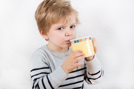 Cute little boy of two years drinking from a cupの写真素材