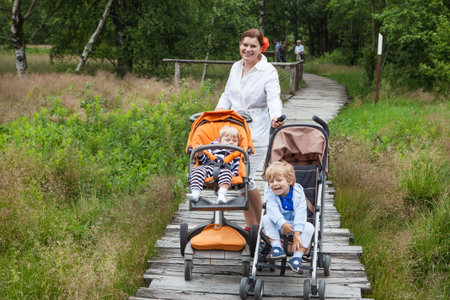 Young mother and two little boys in summer nature park in Germany