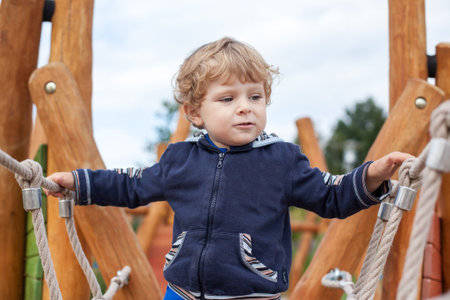 Little toddler boy having fun on playground in summer