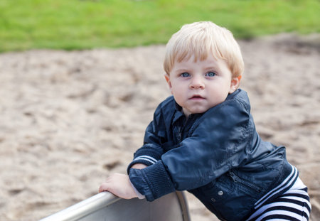 Little toddler boy sitting on playground in summerの写真素材