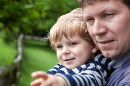 Little boy with blond curly hairs and his father in zooの写真素材