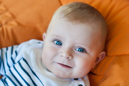 Lovely baby boy outdoor in orange stroller summer