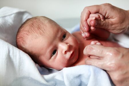 Newborn baby boy only few hours old taking first bathの写真素材
