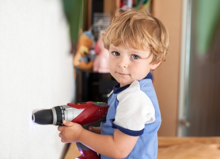 Adorable toddler boy playing with drill at homeの写真素材