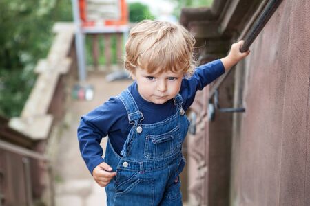 Little toddler boy climbing big stairs in city, Germanyの写真素材