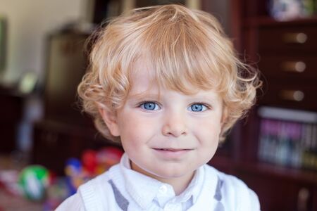 Portrait of blond toddler boy with curly hairs and blue eyesの写真素材