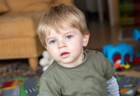 Little toddler boy with blue eyes and blond hair indoor