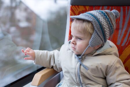 Cute little boy looking out train window outside, while it moving  travelの写真素材
