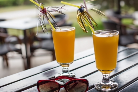 yellow cocktail with straw on wood table in summerの写真素材