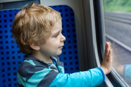 Lovely toddler boy looking out train window outside, while it moving. travelの写真素材