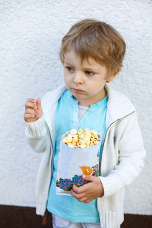 Happy little boy with popcorn bag, eating sweetsの写真素材