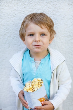 Happy little boy with popcorn bag, eating sweetsの写真素材