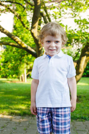 Portrait of smiling happy little boy in summer gardenの写真素材