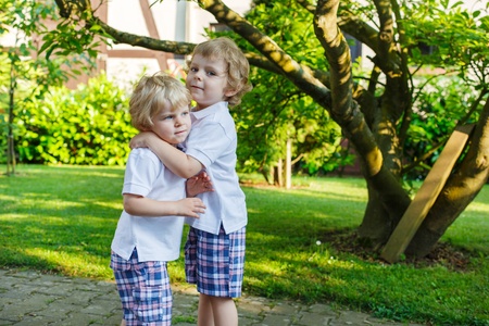 Two little sibling boys having fun outdoors in family look in summerの写真素材