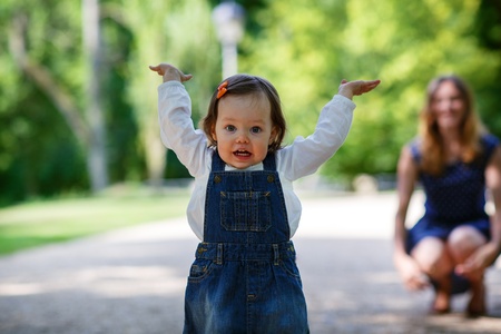 Beautiful mother and little daughter walking together in summer parkの写真素材