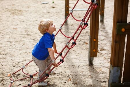 Little toddler boy having fun on playground in summerの写真素材