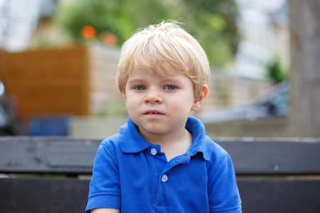 Little cute toddler boy with blond hairs and blue eyes smilingの写真素材