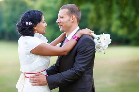 Beautiful indian bride and caucasian groom, in summer parkの写真素材
