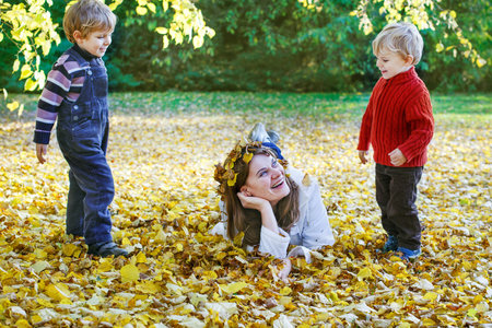 Happy mother with little son having fun in autumn parkの写真素材
