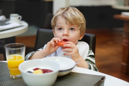 Blond little boy eating french fries in outdoor restaurant.の写真素材