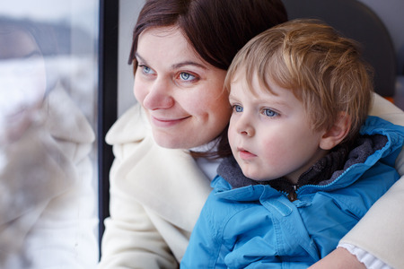 Happy woman and toddler son looking out train window outside, while it moving. travelの写真素材