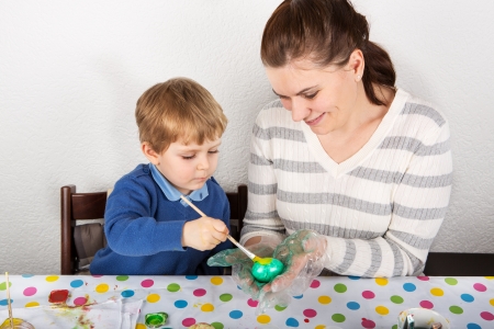 Mother And Son Decorating Easter Eggs On Table indoorの写真素材
