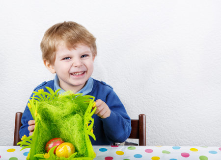 Little toddler boy being happy about Easter egg hunt, traditional action in Germany for Eastern...