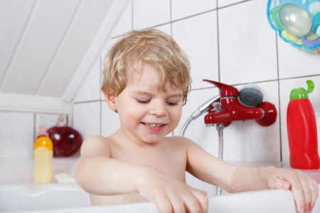 Cute little toddler boy of two years having fun by taking bath in bathtub.の写真素材