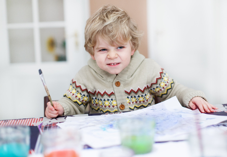 Adorable toddler boy having fun indoor, painting with different paints colorsの写真素材