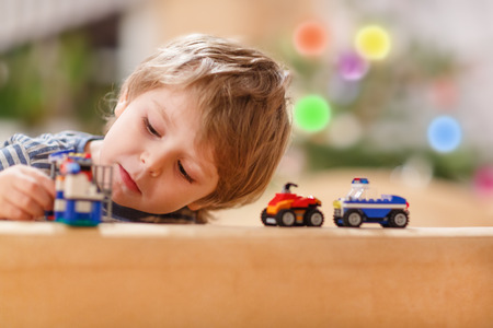 Little blond boy playing with cars and toys at home, indoorの写真素材