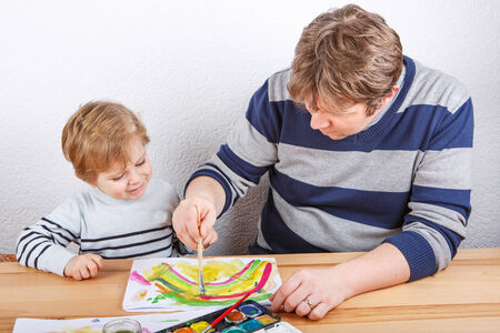 Father and little boy of two years having fun painting at homeの写真素材