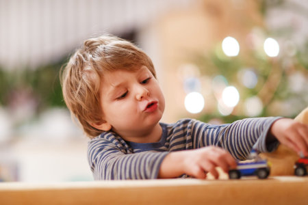 Little blond boy playing with cars and toys at home, indoor