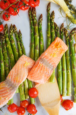 Salmon fish and vegetables: green aspargus, cherry tomatoes and fennel, on oven trayの写真素材