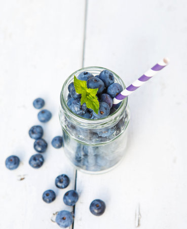Ripe fresh blueberries in glass jar on a wooden table  Healthy breakfast, smoothie in making の写真素材
