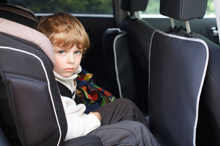 Portrait of little blond boy sitting in safety car seatの写真素材