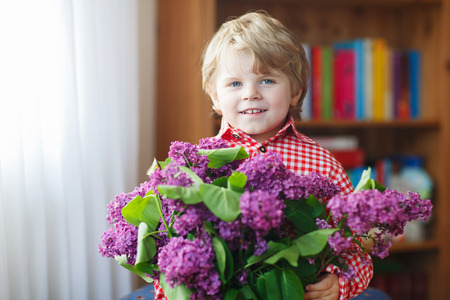 Adorable smiling little boy with blooming lilac flowers, indoor.の写真素材