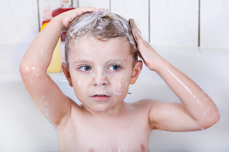 Portrait of lovely little toddler boy  washing hairs with shampoo and taking bath in bathtub.の写真素材