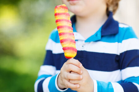 child hands holding colorful fruit ice creamの写真素材