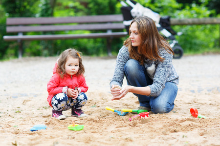 Happy mother and little beautiful daughter playing together on playground in summerの写真素材