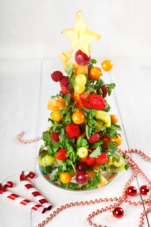 Fruit Christmas tree with different berries, fruits and mint, healthy snack on Christmas table or New Year Eveの写真素材