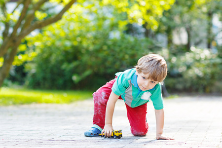 Little child playing with car toy in summer gardenの写真素材