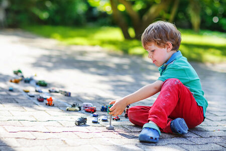 Little child playing with car toy in summer gardenの写真素材