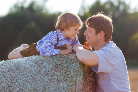 Happy family of two: Young father and his little son having fun on yellow hay field in summerの写真素材