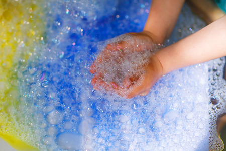 Hands of child playing with colorful soap bubbles.の写真素材